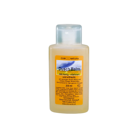eine durchsichtige Flasche mit orangem Etikett und schwarzer schrift Dusch Balm mit Honig Pflegender Honig-Duschbalsam mit naturreinem Bienenhonig in transparenter Flasche. Sanfte Reinigung und vitalisierende Körperpflege aus der Imkerei für die tägliche Anwendung.