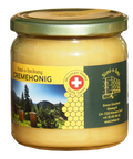 Ein Glas mit Simi-s-Imihung Berg-Cremehonig mit goldenem Deckel. Das Etikett zeigt eine Schweizer Flagge, eine malerische Berglandschaft, ein Wabenmuster und Kontaktdaten. Der Honig im Inneren ist hellgelb und cremig. Ausgezeichnet mit dem Schweizer Qualit 100% Swiss Mountain Honey