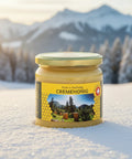 Ein Honigglas mit „Cremehoning“ und einem gelben Etikett mit Berglandschaft, Bienbeuten, Wabenmuster und einem Schweizer Qualitätssiegel, das 100 % Schweizer Berghonig anzeigt.