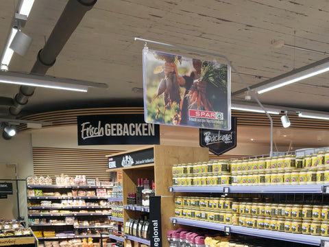 Honiggläser im Regal eines SPAR-Supermarkts, Bäckereiabteilung im Hintergrund, Präsentation von Schweizer Honig im Detailhandel.